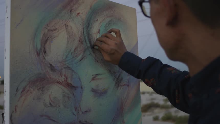 An artist draws on a canvas outside