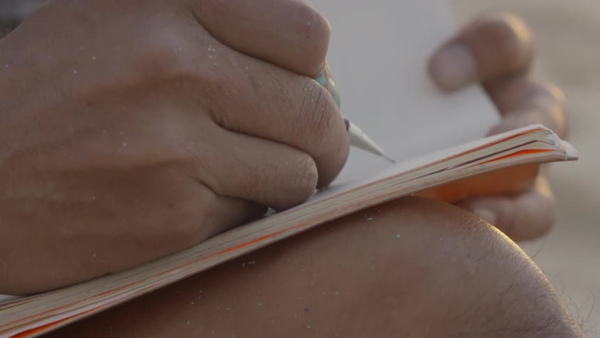 Man writes in a notebook with a pen