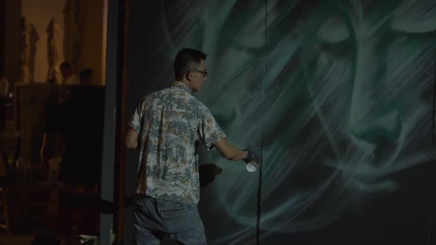 An artist uses spray paint on a wall