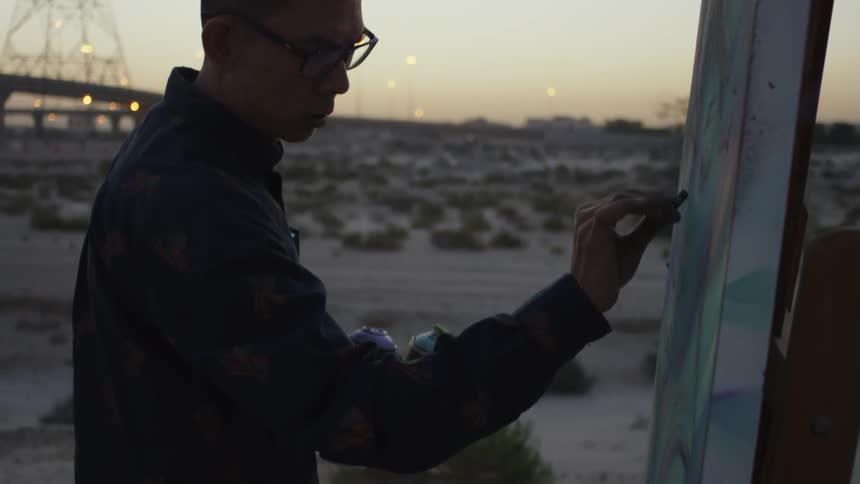 A man is drawing with charcoal outside