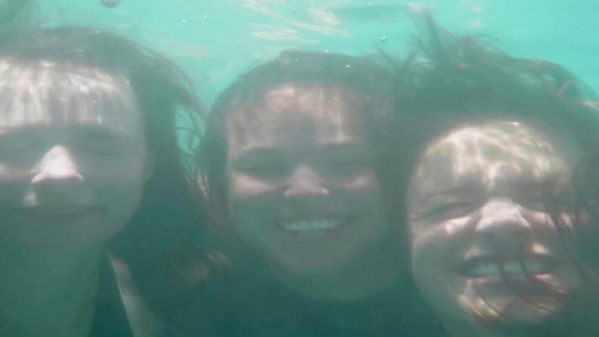Friends smile while swimming underwater