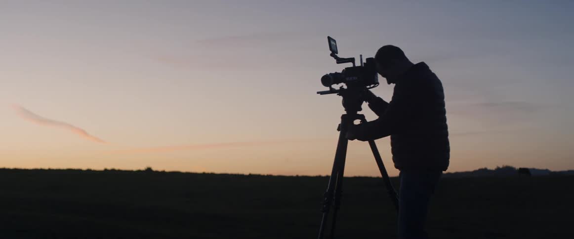 A photographer takes a picture outside at dusk
