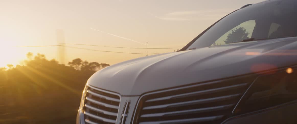 The sun shines on rural landscape as an suv travels down the road