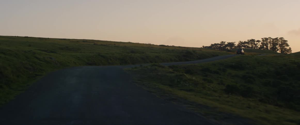 A truck drives on a rural road at sunset