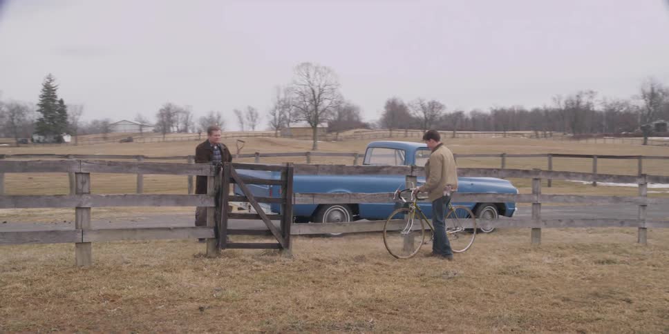 A man is walking his bike toward a truck