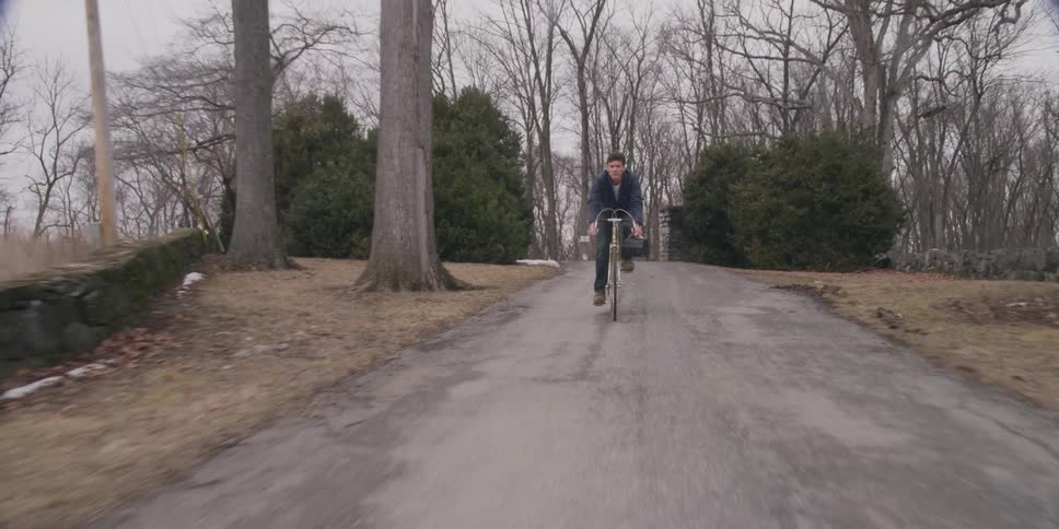 Man riding his bike down road on a cloudy day