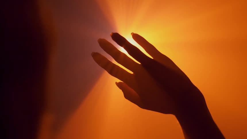 A woman holds her hand up to a bright light