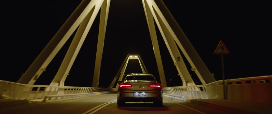 A car drives over a city bridge at night
