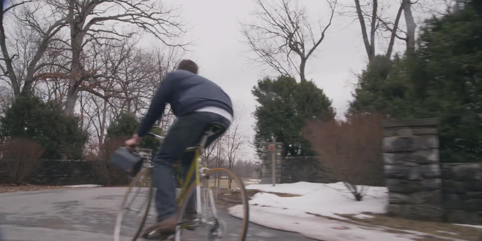 A young man riding his bicycle down a road during the winter