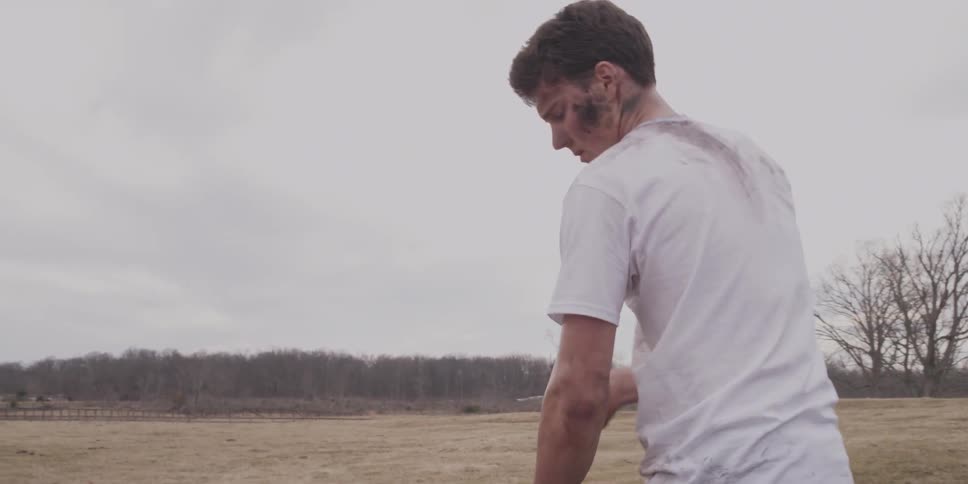 Man digging in a field looks over on a cloudy day