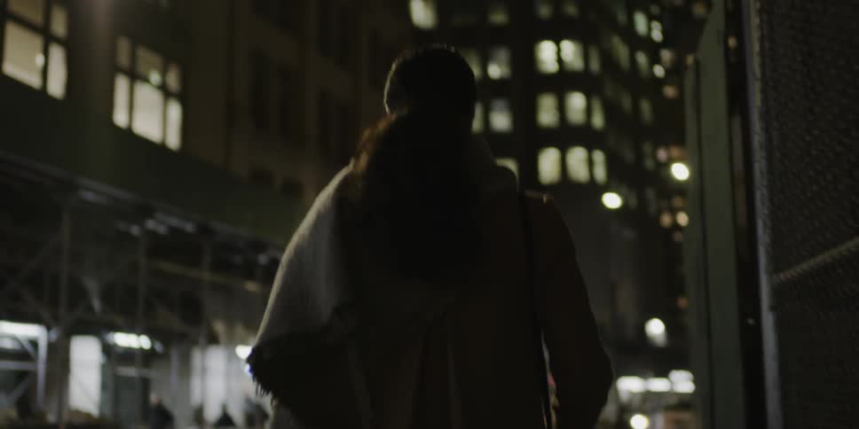 Woman walks down a city street at night