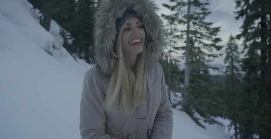 Woman in hooded jacket smiles as she walks in the snow