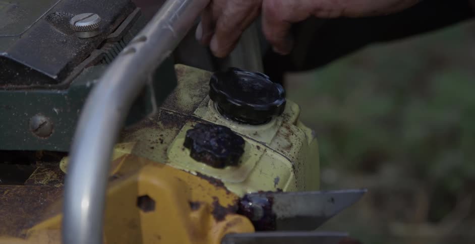 A man tightens the gas cap on a chainsaw