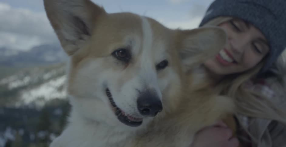 A woman is standing outside holding a corgi on a winter day