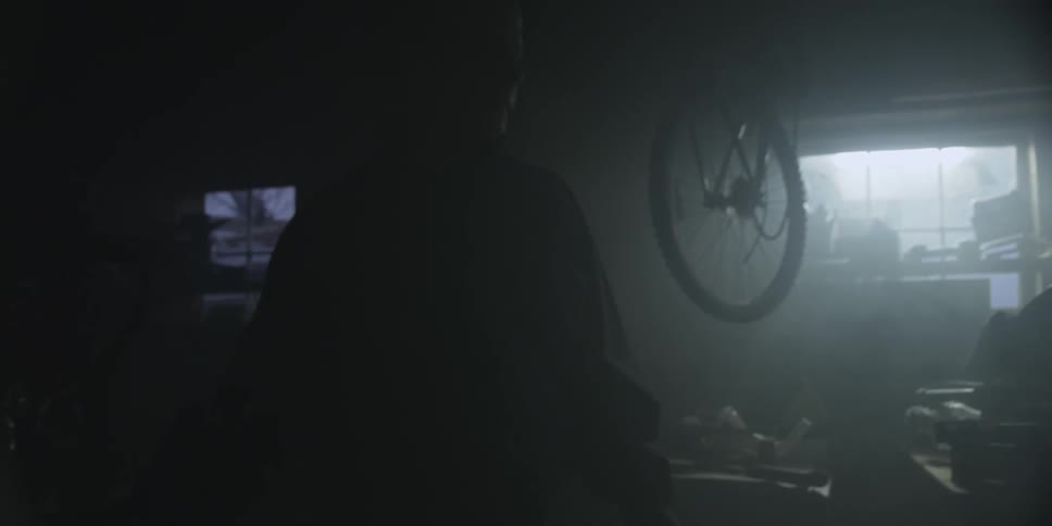 A man walking through a shadowy garage