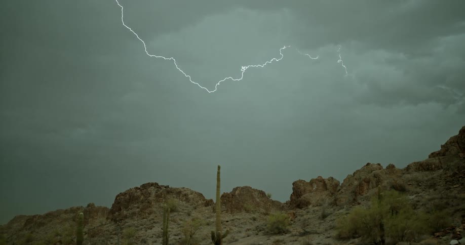 Lighting flashes in the clouds above the mountain
