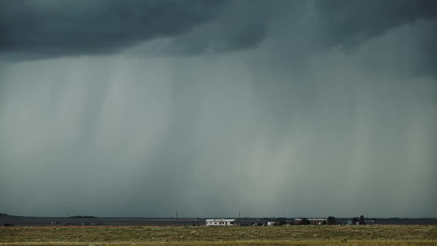 The large storm clouds shoot lightning and rain down