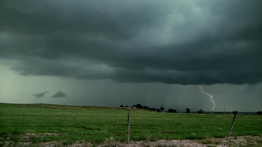 The storm clouds surround the green fields ahead