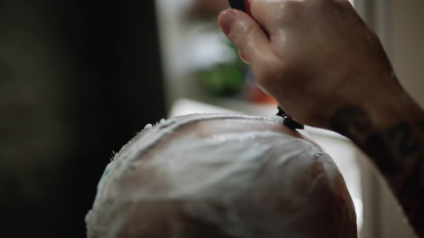 A person is shaving their head bald