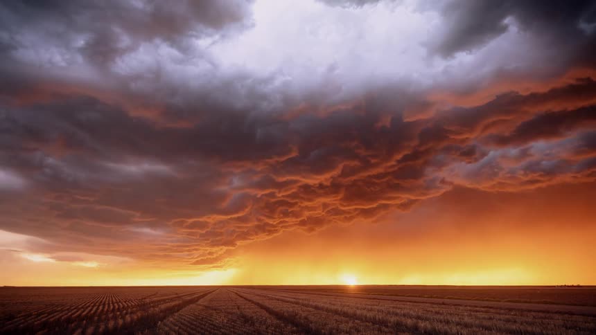 A storm is blowing across a farm fields at dusk