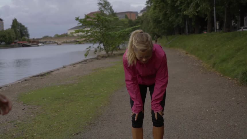 A woman is pulling up lame as she jogs with a friend on an overcast day
