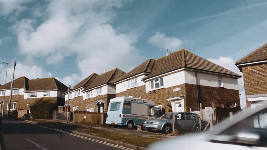 A car drives uphill past the homes