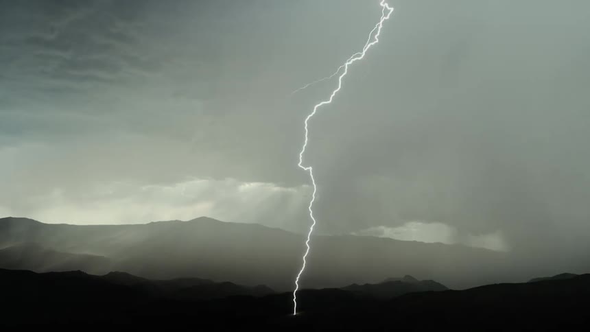 A long lightning bolt flashes in the rainy sky