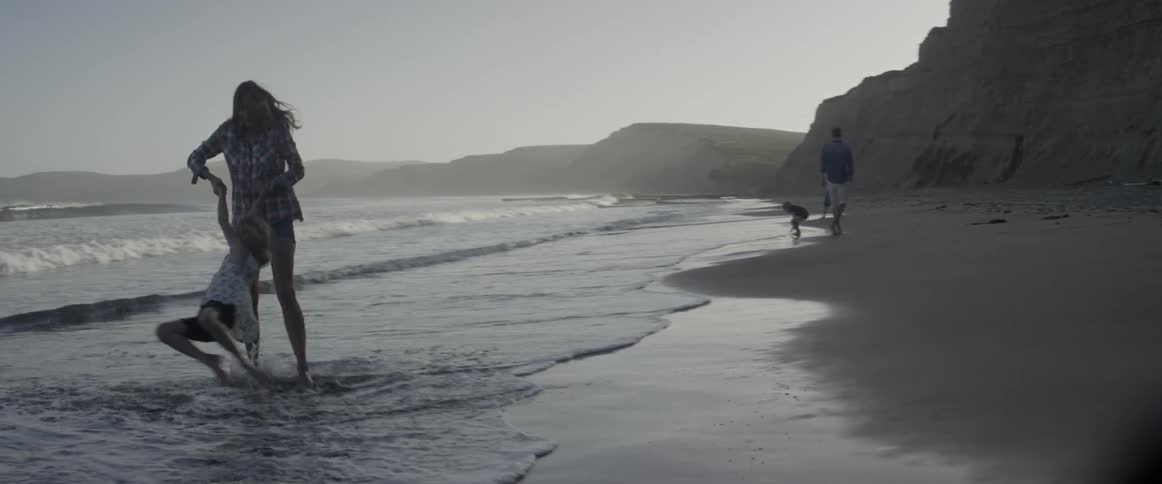 A mother and daughter are playing near the waves at the beach in daylight