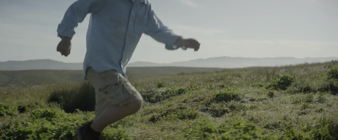 A child runs uphill through the grass