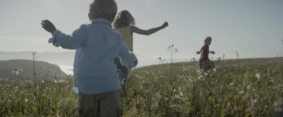 Children run through a grassy field