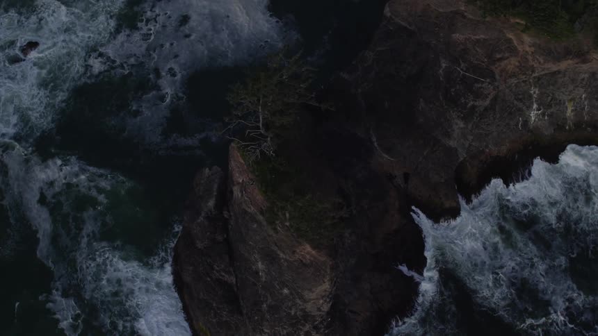 The waves crash against the tall rocks