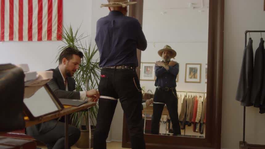 A man is being fitted for some clothing in a shop