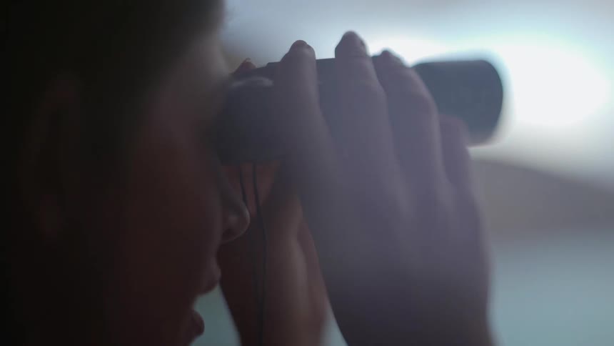 Woman holds binoculars to her eyes as she looks to the distance
