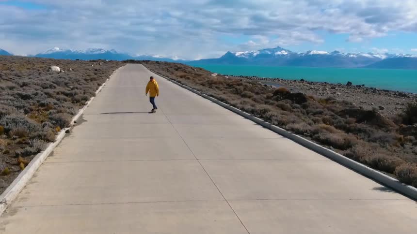 A person in a yellow jacket rides a skateboard
