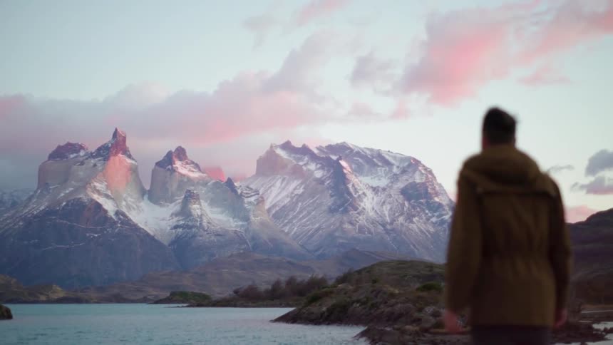 A man overlooks a lake and snowy mountains
