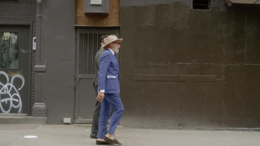 Two men walk together down the sidewalk