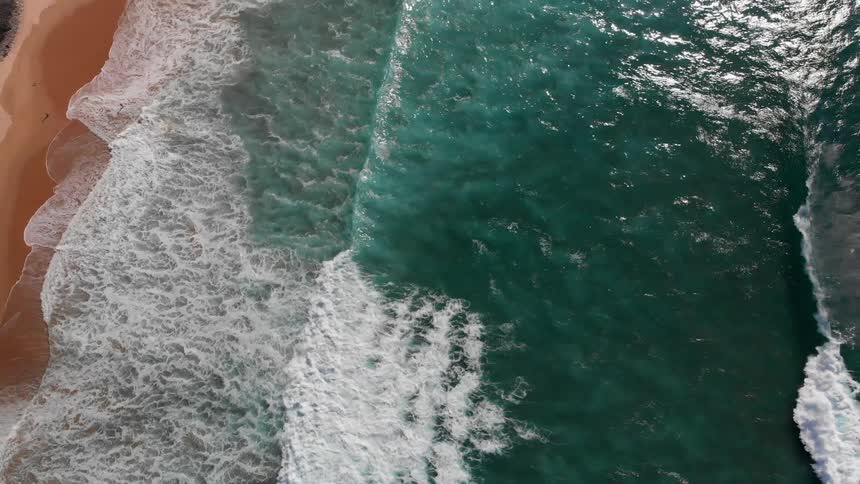 The clear waters crash against the sand on the beach