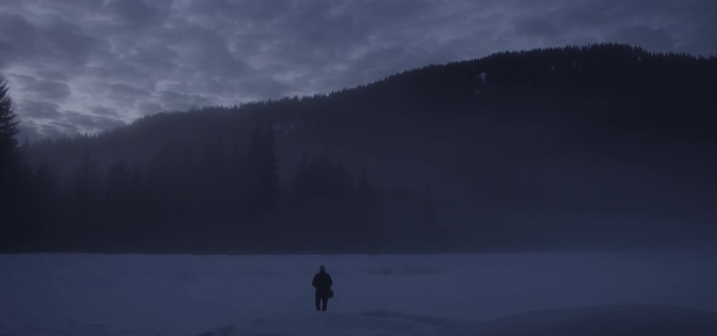 A person is hiking in the snow at sunset