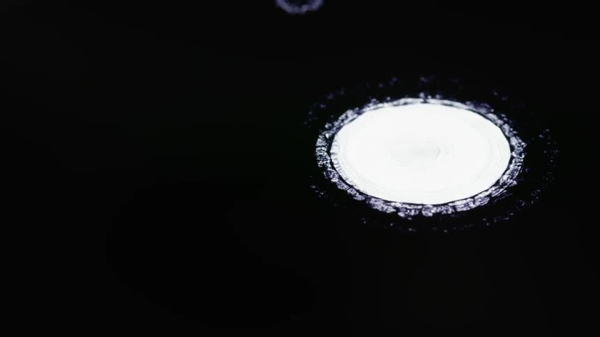 White paint falls in the dark liquid