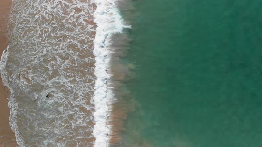 Waves crash into a sandy beach
