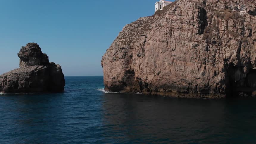 A building sits on top of a cliff on the ocean