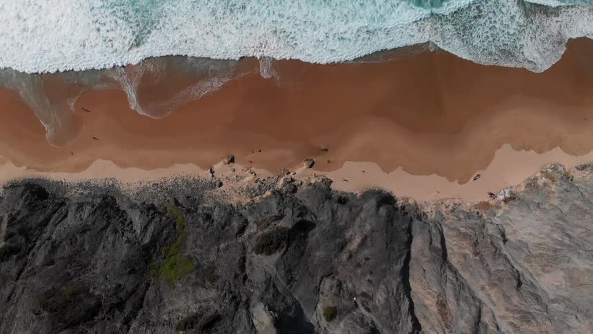 Foamy waves crash into the sandy beach