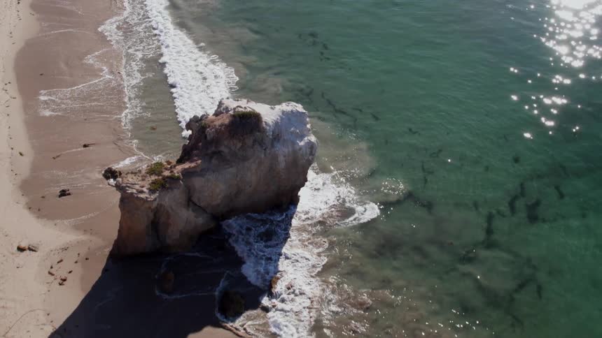 The waves crash against the beach below