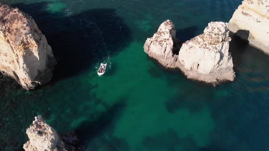 A boat travels through clear water around rock formations