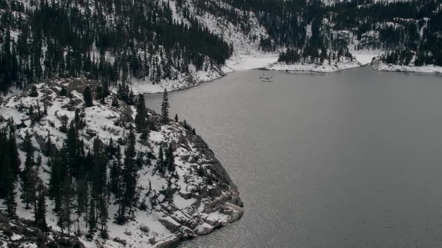 Calm lake sits next to snow covered mountains