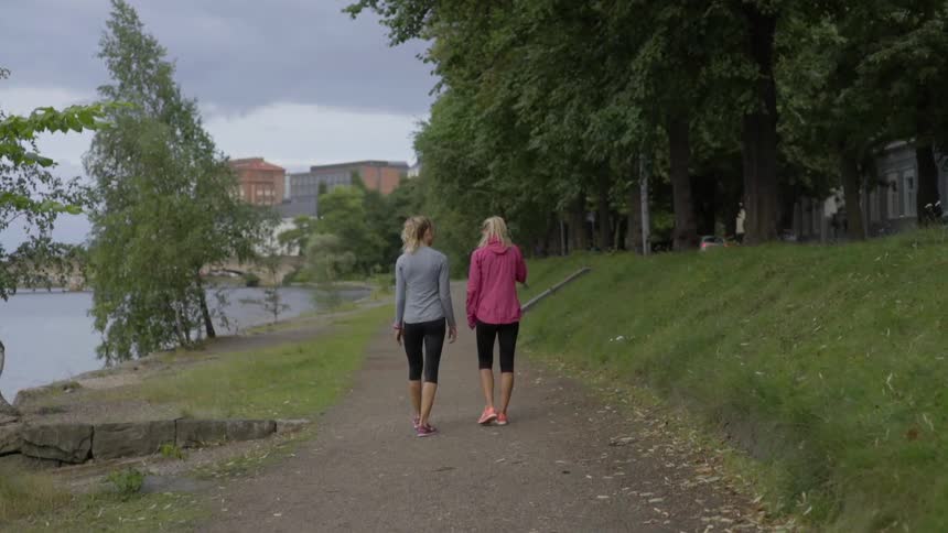 Two blonde fitness partners cool down by walking outdoors after a cardio run.