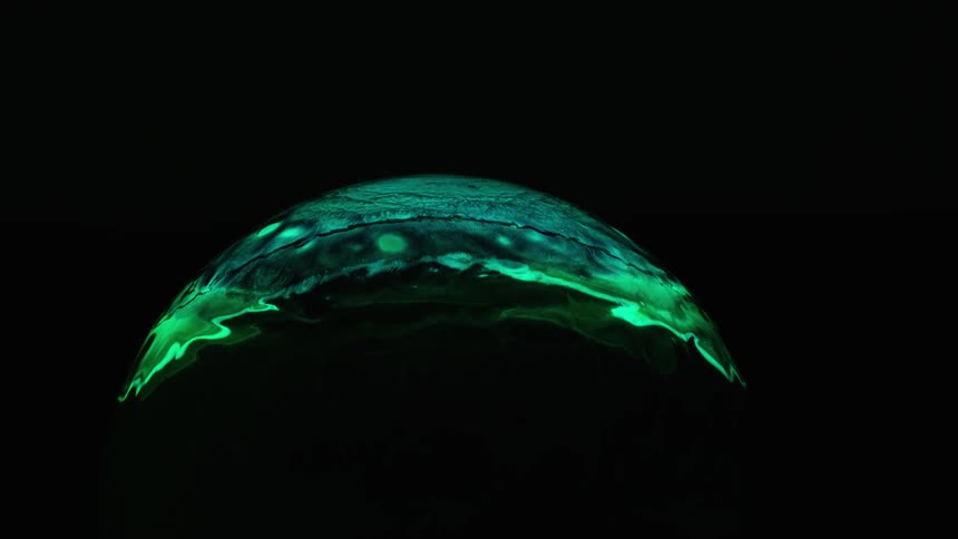 Green colored liquid spreads over a round object
