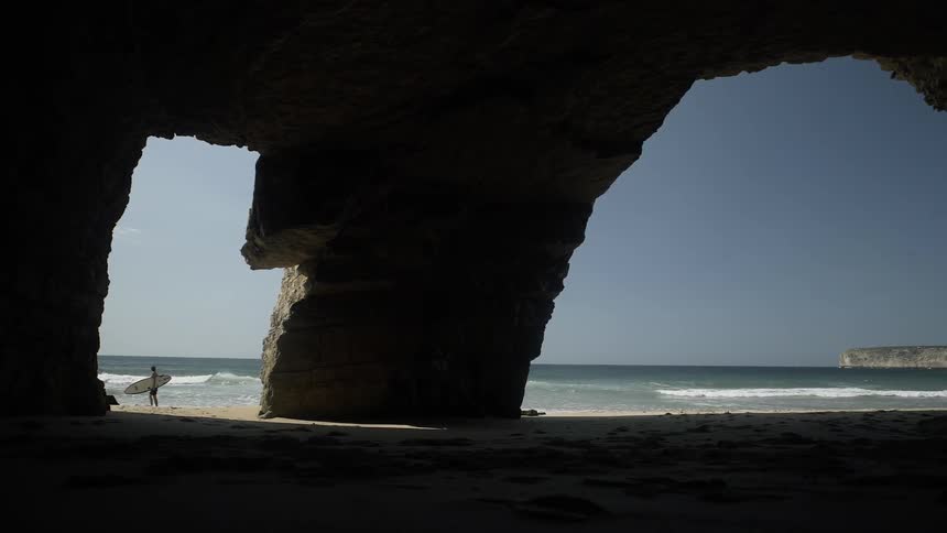 A surfer walks on a beach