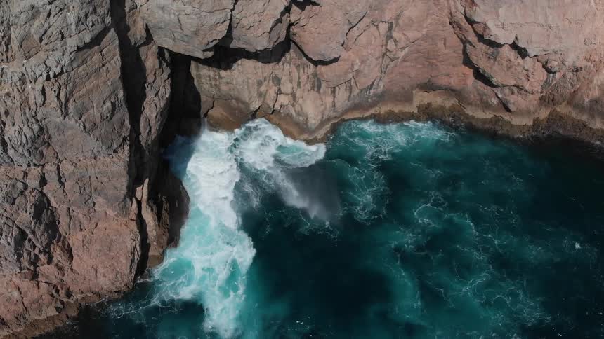 Water splashes against tall rock formations