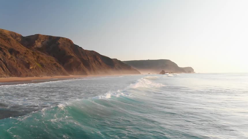 A wave is crashing towards the shore on a sunny day